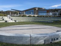 a very large cement circular stage set up in the grass near an outdoor patio with stairs and benches