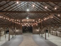 the inside of a large barn with wooden beams and ceiling lights, and large chandelier