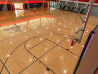 a gym floor with wood look and blue lines on the floor and inside, an air filled basketball court is shown