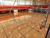 a gym floor with wood look and blue lines on the floor and inside, an air filled basketball court is shown