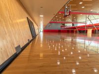 a gym with red and black walls and hardwood floors with a basketball hoop attached to the ceiling