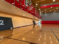 a gym with a wooden floor and red lighting fixtures on the wall and flooring