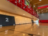 a gym with a wooden floor and red lighting fixtures on the wall and flooring