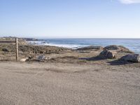 a surfboard sitting in a corner by the water on the beach and some rocks