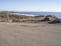 a surfboard sitting in a corner by the water on the beach and some rocks