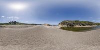 a beach scene with shallow water, trees and rocks and sandbanks, as seen through 360 glasses