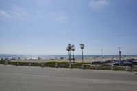 the ocean and beach are visible in this shot from a sidewalk near the parking lot