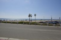 the ocean and beach are visible in this shot from a sidewalk near the parking lot