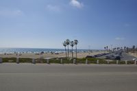 the ocean and beach are visible in this shot from a sidewalk near the parking lot