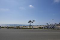 the ocean and beach are visible in this shot from a sidewalk near the parking lot