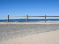 a paved beach with a fence in front of it and the ocean in the distance