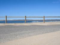 a paved beach with a fence in front of it and the ocean in the distance