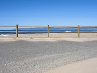 a paved beach with a fence in front of it and the ocean in the distance