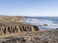 an ocean and some cliffs with a light house in the distance in the distance is a cliff formation