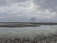 a cloudy view of a large area of rocks and water in the foreground are several large puddles in the ground