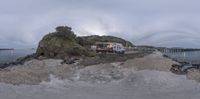 a panorama of a beach next to the sea and a mountaintop with a pier