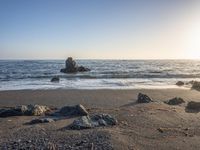 a grassy field by the shore and a cliff with rocks in the ocean in the background