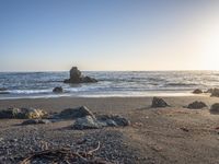 a grassy field by the shore and a cliff with rocks in the ocean in the background