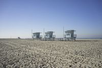 people walk on sand at a beach, near the ocean in the distance is a sky with few cloudless, and blue skies