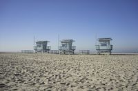 people walk on sand at a beach, near the ocean in the distance is a sky with few cloudless, and blue skies