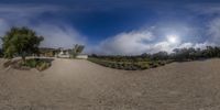 a mirror image of a beach next to house and grass field in front of some clouds