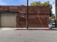 a red fire hydrant sitting next to an empty brick building on a sidewalk and parked cars