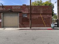 a red fire hydrant sitting next to an empty brick building on a sidewalk and parked cars