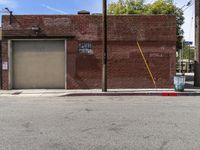 a red fire hydrant sitting next to an empty brick building on a sidewalk and parked cars