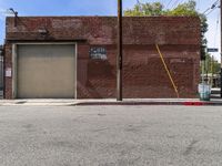 a red fire hydrant sitting next to an empty brick building on a sidewalk and parked cars