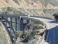 an overpass that is on top of a mountain with a train track and a yellow car