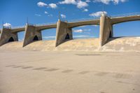 the skateboarder is riding around on the concrete ramp in front of a bridge