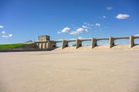 a photo of a building and some sand and water in the desert of an open lot