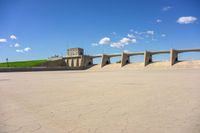 a photo of a building and some sand and water in the desert of an open lot