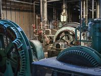 a large blue machine in a building with pipes and valves to be used as machines