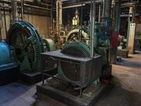 a large blue machine in a building with pipes and valves to be used as machines