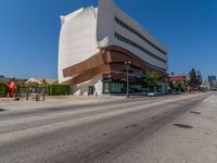 a very big building is on the corner of a street near a bus stop and road