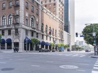 a couple of people crossing the street while a man crosses at an intersection near buildings