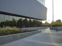 a large building with tall windows next to some bushes and a sidewalk with a planter