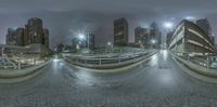 a city at night showing the light on a street bridge and a parking lot with cars parked