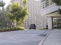 an suv is parked in front of some tall buildings as a woman walks on her cell phone