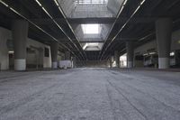 the inside of an empty building looking into an empty parking lot with vehicles parked underneath it