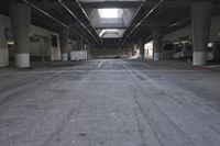 the inside of an empty building looking into an empty parking lot with vehicles parked underneath it