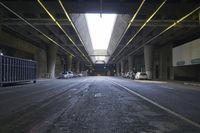 the inside of an empty building looking into an empty parking lot with vehicles parked underneath it