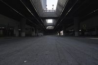 the inside of an empty building looking into an empty parking lot with vehicles parked underneath it