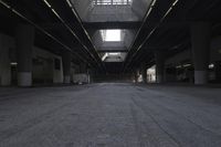 the inside of an empty building looking into an empty parking lot with vehicles parked underneath it