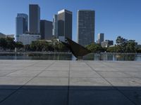 a person with their umbrella on the ground near water and tall buildings behind them in a city