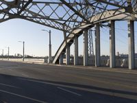 view from inside the tunnel to underneath a bridge on a sunny day with buildings in the background