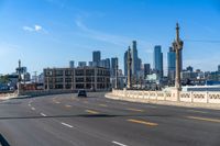 the city skyline stands in a blue sky with clouds over the street and yellow lines on the road