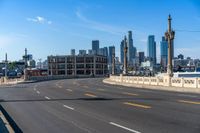 the city skyline stands in a blue sky with clouds over the street and yellow lines on the road