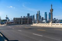 the city skyline stands in a blue sky with clouds over the street and yellow lines on the road